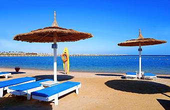 Sandy beach with blue loungers and straw umbrellas facing the sea