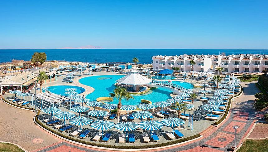 Large seaside hotel complex with multiple pools, sun loungers, and umbrellas overlooking the Red Sea coast