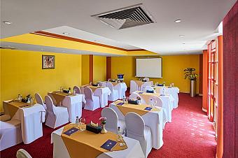 Meeting room with yellow walls, red carpet, and neatly arranged tables and chairs