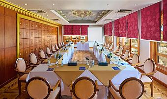 Conference room with long tables arranged in a U-shape, elegant decor, and projector setup