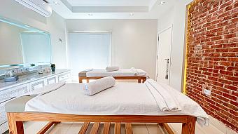 Bright spa room with two massage tables, white towels, and a brick accent wall for relaxation sessions