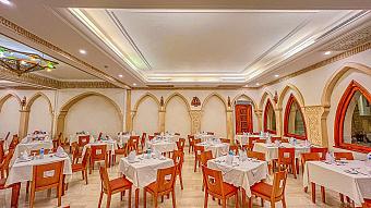 Indoor dining room with arched windows, neatly arranged tables, and warm lighting