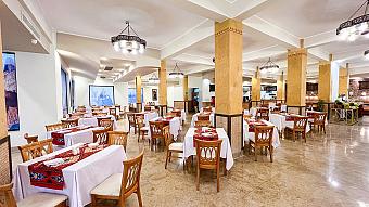 Spacious restaurant with wooden chairs, white tablecloths, and warm lighting, ideal for group dining after training sessions