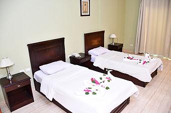 Hotel room with two single beds, wooden furniture, and towel swans decorated with flowers
