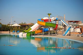 Outdoor pool area with colorful water slides and lounge chairs, ideal for athlete relaxation after training