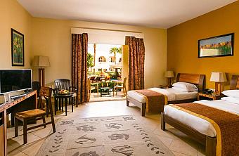 Family room with two single beds, pool view balcony, and wooden furniture