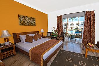 Hotel room with king-size bed, warm decor, and direct access to poolside terrace