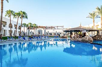 Resort swimming pool with sun loungers, umbrellas, and a shaded swim-up bar area