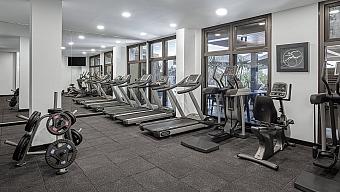 Hotel gym with treadmills, ellipticals, and weight plates for athlete workout during training camp