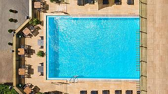 Top-down view of outdoor blue pool with deck chairs and tables for training camp recovery swim