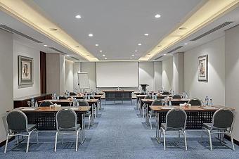 Conference room with classroom tables, water bottles, projector screen and flip chart for a coaching session