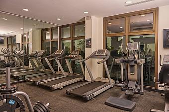 Hotel gym with treadmills, elliptical machine, weights and mirrored wall for a workout during training camp