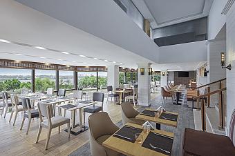 Hotel restaurant with set tables and large windows overlooking trees and river, for training camp meals