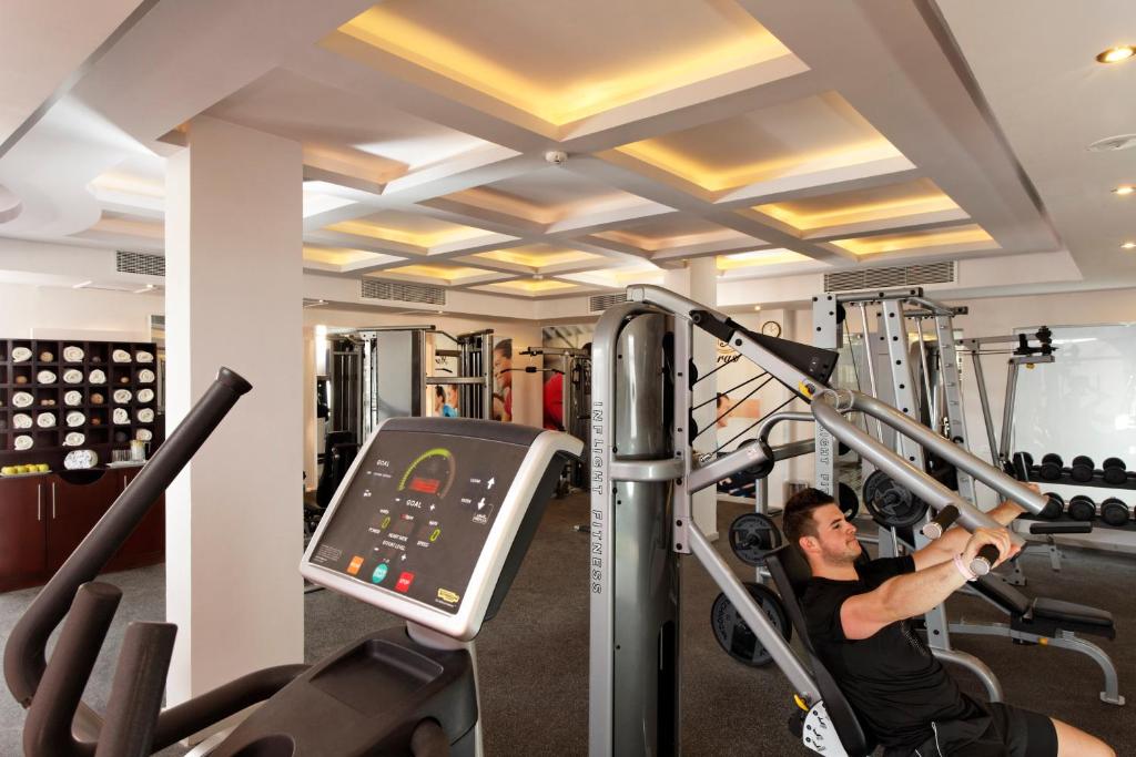 Fitnessraum mit Kraftgeräten und Kurzhanteln; eine Person trainiert im Innenbereich.