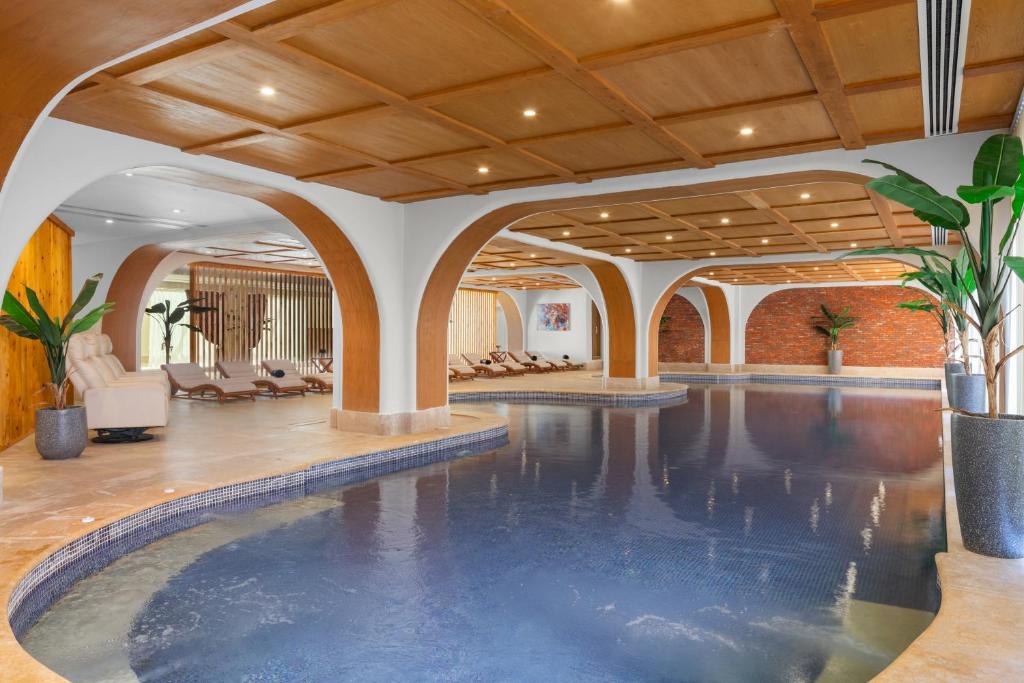 Indoor-Pool mit Liegen und Sitzbereichen unter Bögen zur Entspannung und Regeneration.