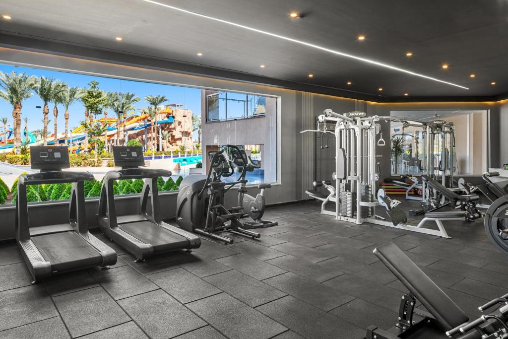 Moderner Fitnessraum mit Laufbändern, Cardio-Geräten und Kraftstationen mit Blick auf den Wasserpark des Resorts.
