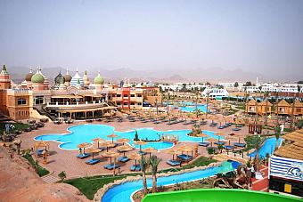Panoramablick auf Resort-Pools und Wasserparkbereich mit Sonnenliegen und gestalteten Wegen.