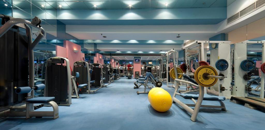Fitnessraum mit Kraftgeräten, Bankdrückstation, Spiegeln und Gymnastikball für Workout-Training.