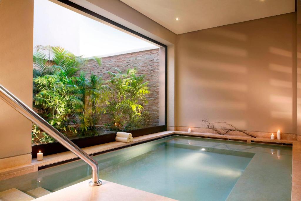 Indoor-Spa-Pool mit Handlauf, Kerzen und Blick in einen bepflanzten Innenhof.