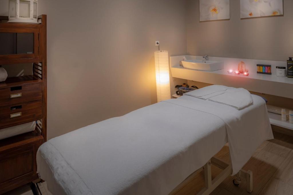 Spa-Behandlungsraum mit Massageliege, Waschtisch, Handtüchern und weicher Beleuchtung.