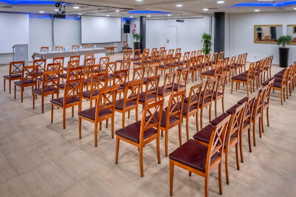 Konferenzraum mit Stuhlreihen, Projektionsleinwand und vorderem Tisch für Präsentationen.