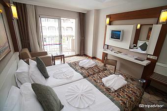 Twin room with balcony, desk, TV and seating area for training camp accommodation.