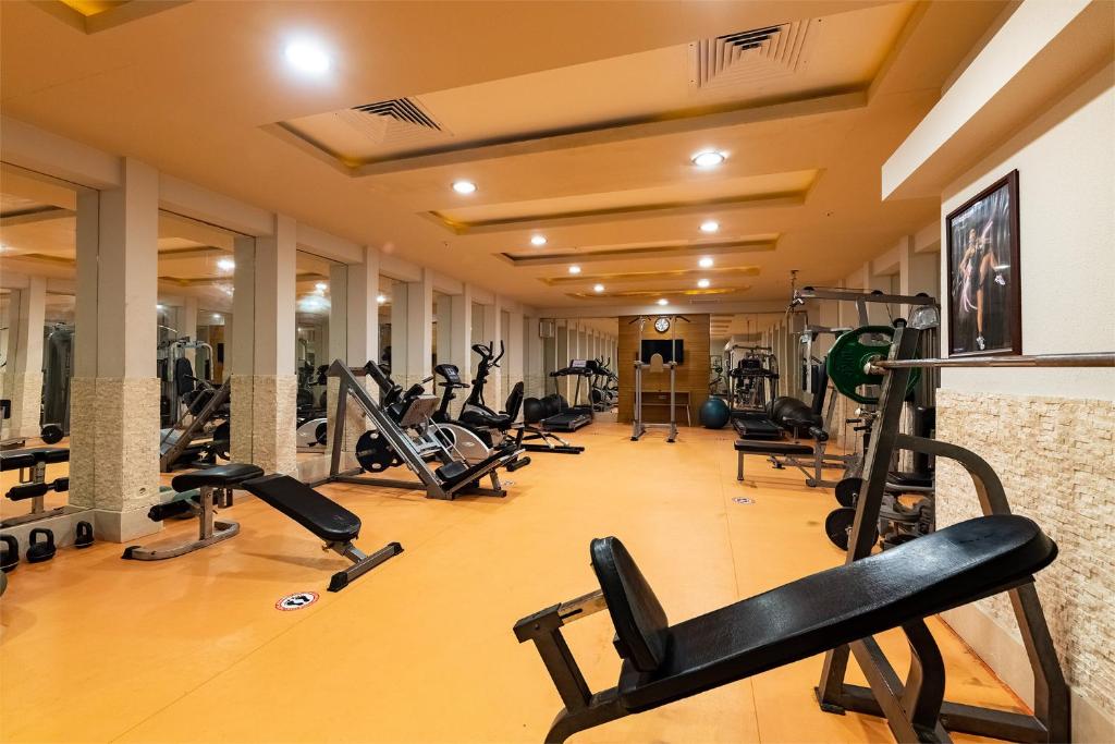 Salle de fitness avec bancs, machines et mur miroir pour entraînement de musculation.