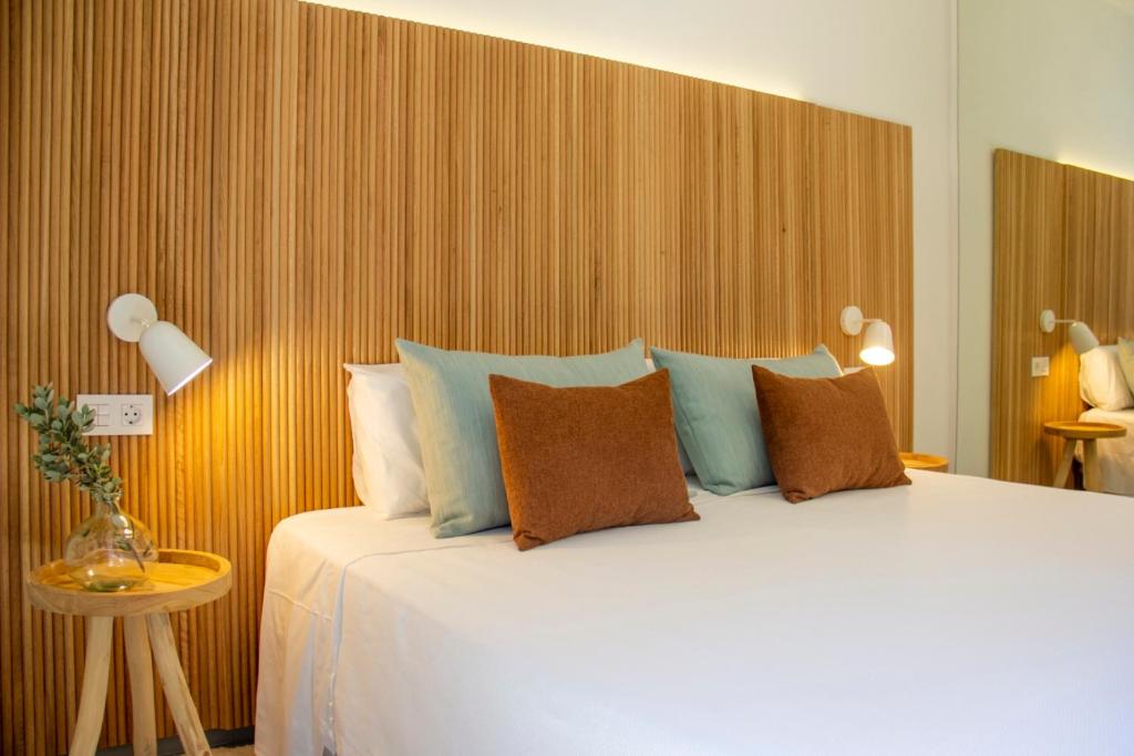 Chambre double moderne avec tête de lit en bois, lampes de chevet et coussins décoratifs.