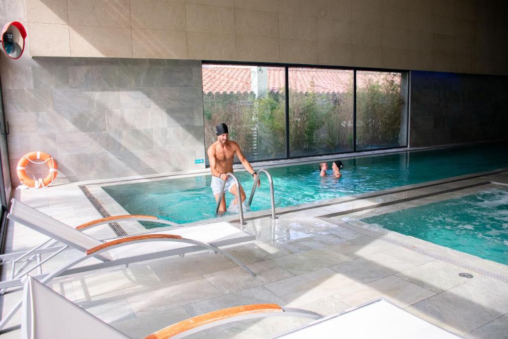 Piscine spa intérieure avec chaises longues et personnes dans l'eau.