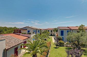 Vue sur les villas du complexe avec jardins, palmiers et toits en tuiles.