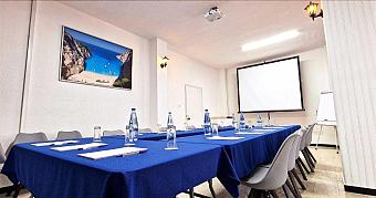 Meeting room with U-shaped table setup, projector screen and flip chart.