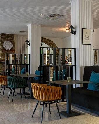 Lobby lounge with dining tables, upholstered seating and partition screens.