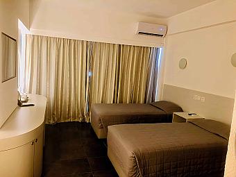 Twin room with two single beds, air conditioning and full-width curtains.