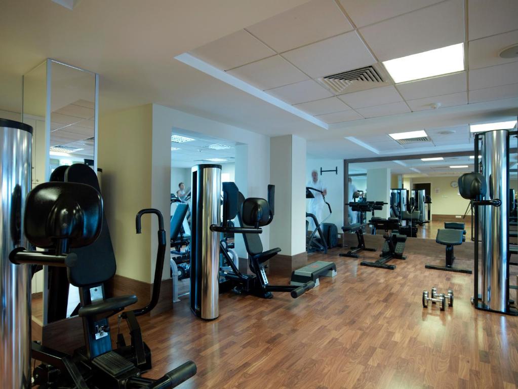 Fitnessraum mit Kraftgeräten, Hanteln und verspiegeltem Trainingsbereich.