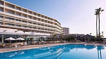 Wide exterior view of the hotel, pool deck and seafront.