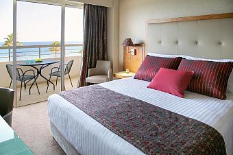 Guest room with sea-view balcony, double bed and seating area.