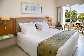 Guest room with double bed, balcony seating and tree view.