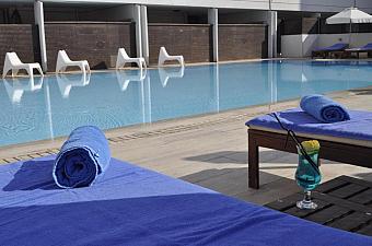 Outdoor pool with sun loungers, towels and a drink by the deck.