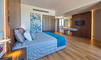 Spacious guest room with double bed, desk and wood-paneled walls.