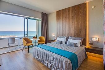 Guest room with double bed, balcony seating and sea view.