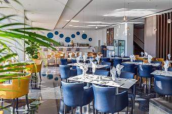 Restaurant dining area with bar, table settings and lounge seating.