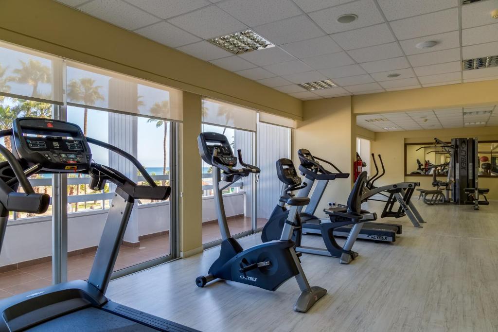 Fitnessraum mit Cardio- und Kraftgeräten an großen Fenstern zur Uferseite.