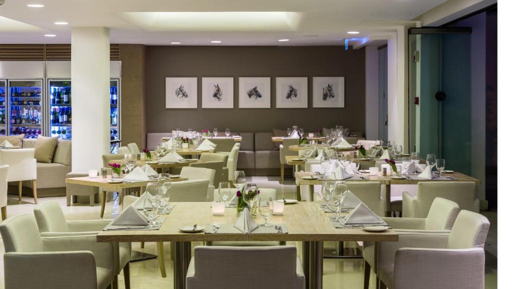 Restaurant dining room with set tables, upholstered chairs and framed wall art.