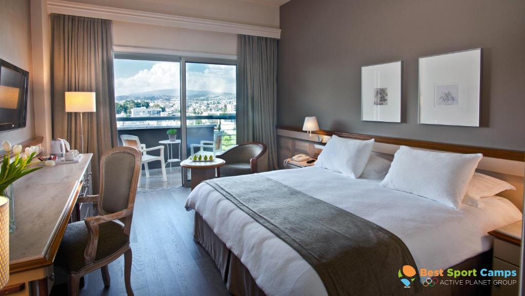 Guest room with double bed, desk and balcony overlooking the city.