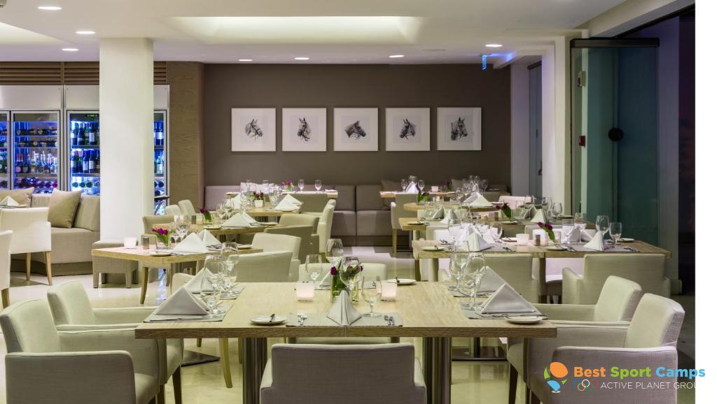 Restaurant dining room with set tables, upholstered chairs and framed wall art.
