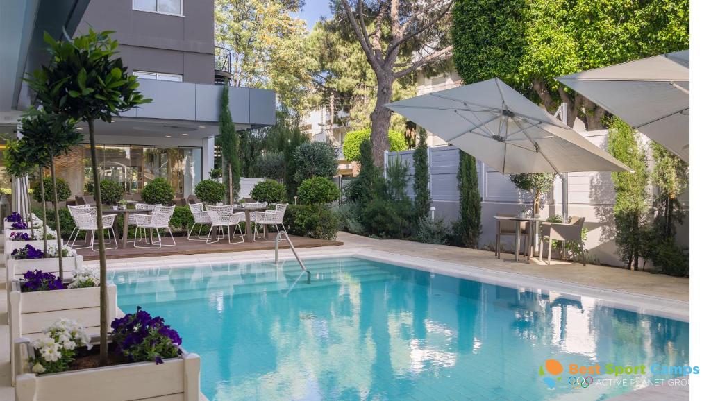 Outdoor pool with surrounding deck, umbrellas and garden seating.