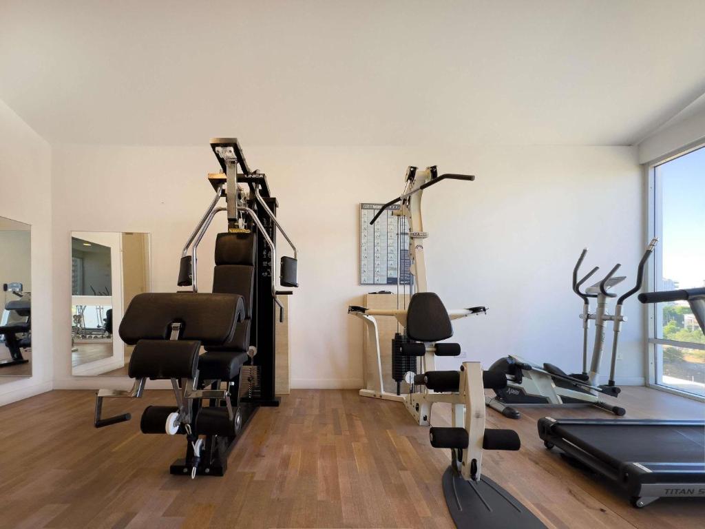Fitness room with strength machines, elliptical trainer and treadmill beside large windows.