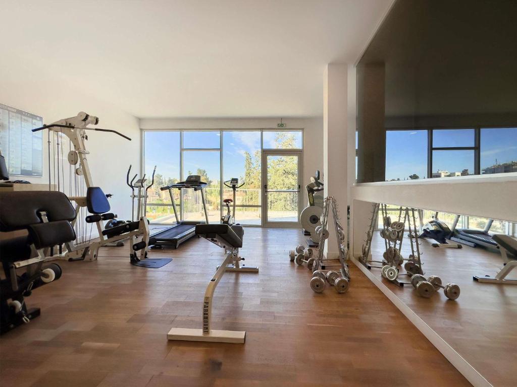 Hotel gym with cardio machines, weights, strength equipment and mirrored wall for workouts.