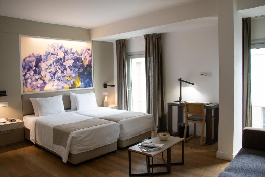 Bright guest room with twin beds, desk, sofa and large floral wall art.