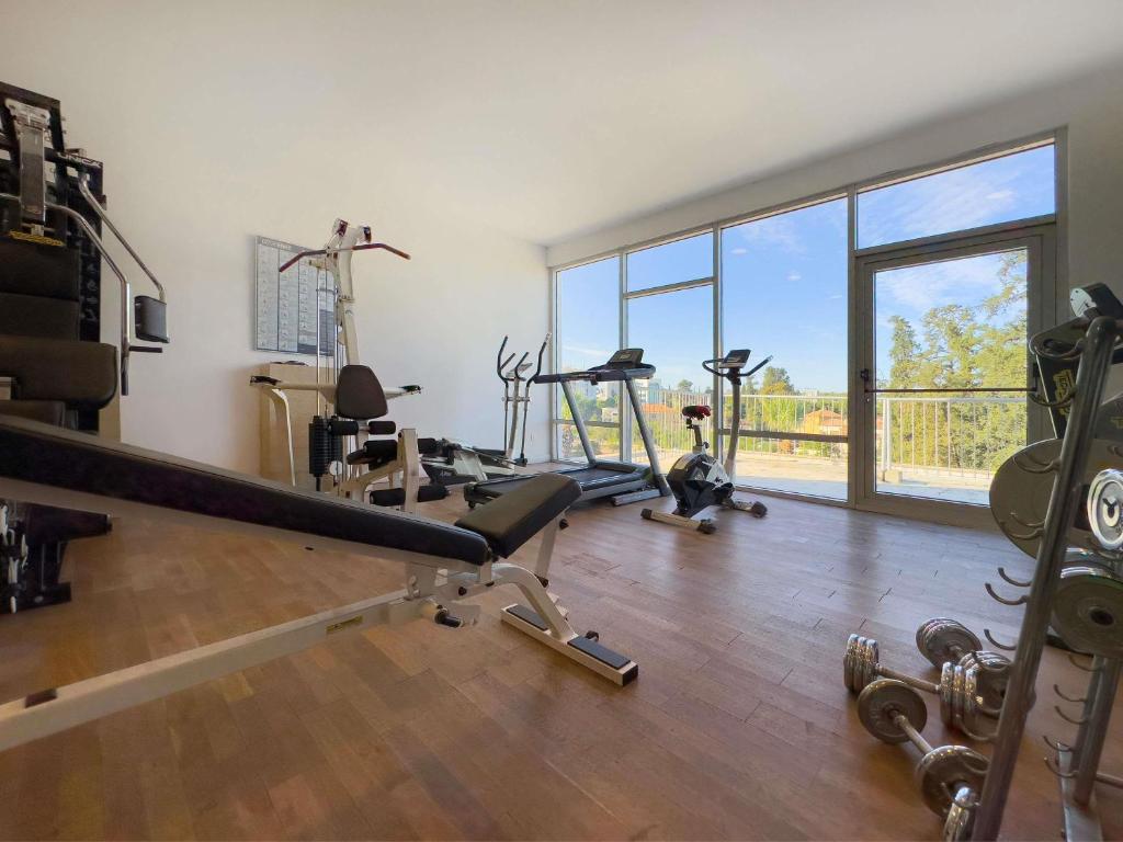 Gym with bench, treadmill, bike, free weights and floor-to-ceiling windows.